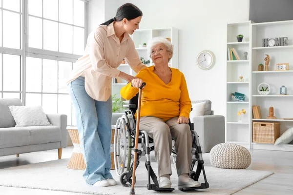 Senior woman in wheelchair with stick and her daughter at home