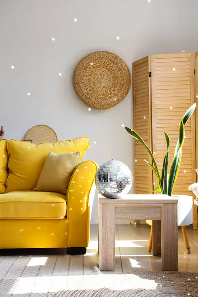 Interior of modern living room with yellow sofa and disco ball on coffee table