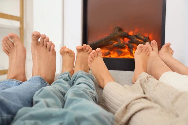 Happy family warming legs near fireplace at home, closeup