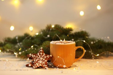 Beyaz ahşap masanın üzerinde zencefilli kurabiye ve bulanık Noel arkaplanı ile bir fincan sıcak kakao.