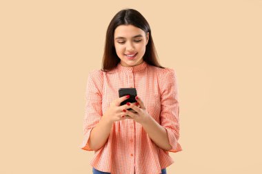 Bej arka planda cep telefonu kullanan genç bir kadın. Çevrimiçi randevu kavramı