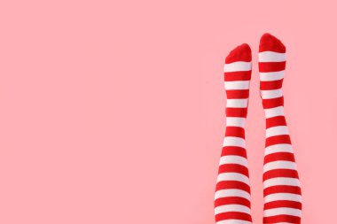 Pembe arka planda Noel çoraplı kadın bacakları