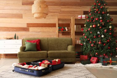 Noel için dekore edilmiş oturma odasında içinde eşyalar ve hediye kutuları olan bavul.