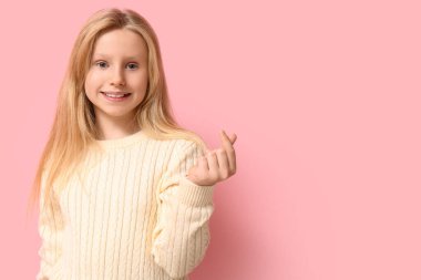 Şirin küçük kız pembe arka planda kalp hareketi gösteriyor. Sevgililer Günü kutlaması