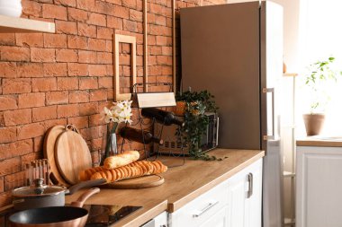 Havalı buzdolabı, tezgah, mikrodalga fırın ve hamur işi olan mutfağın içi.