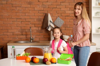 Anne, küçük kızı için mutfakta öğle yemeği hazırlıyor.