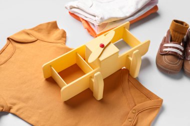 Beyaz arka planda bebek kıyafetleri, patik ve oyuncak uçak kompozisyonu, yakın plan.