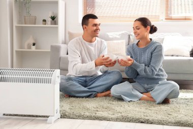 Evde kaloriferin yanında çay ısıtan genç bir çift.