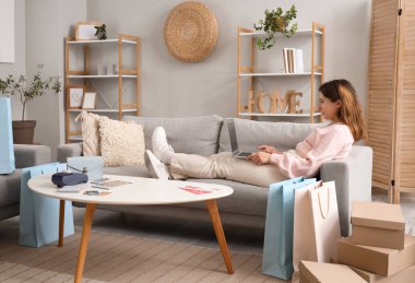 Bilgisayarlı genç bir kadın internette alışveriş yapıyor.