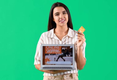 Yeşil arka planda kredi kartı ve laptopu olan genç bir kadın. İnternetten alışveriş