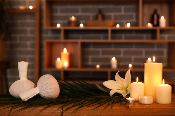 Spa composition with flower and burning candles on table in dark salon, closeup