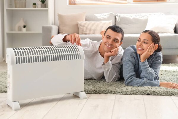 Young couple warming near radiator at home