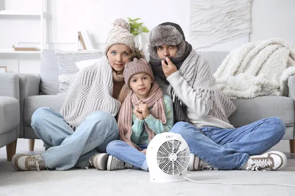 Fryst Familj Vinterkläder Uppvärmning Nära Elektrisk Fläkt Värmare Hemma — Stockfoto
