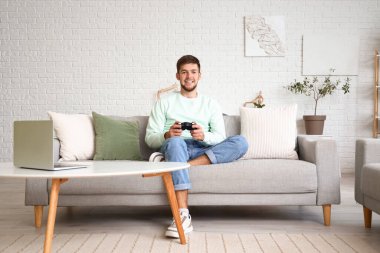 Genç sakallı adam evde video oyunu oynuyor.