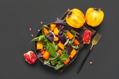 Bir tabak lezzetli salata, hurma, nar tohumu ve siyah arkaplanda soğan.