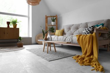 Rahat beyaz kanepesi, sörf tahtası ve dekoruyla aydınlık oturma odasının içinde.