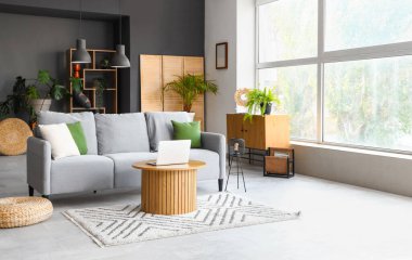 Kahve masasında gri kanepe ve dizüstü bilgisayarı olan modern oturma odası.