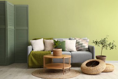 Rahat gri kanepesi, çiçekleri ve ahşap sehpası olan oturma odasının içinde.