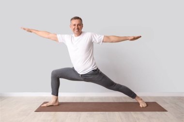 Olgun adam ışık duvarının yanında yoga yapıyor.