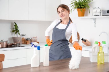 Mutfakta pp-tozu olan kadın hademe masasını temizliyor.