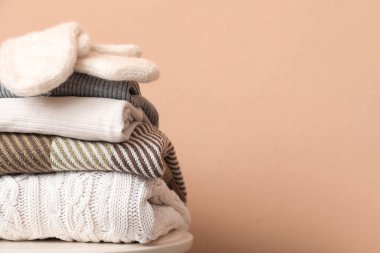 Bej arka planda eldivenli katlanmış süveter yığını.