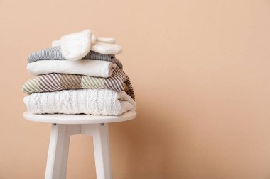 Bej arka planda eldivenli katlanmış süveter yığını.