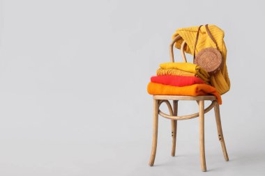 Beyaz arka planda, koltukta çantalı kazaklar yığılmış.