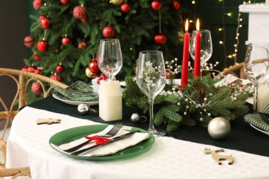 Noel çelengi ve yanan mumlarla süslü masa seti, yakın plan.