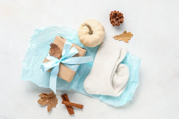 Beautiful composition with warm socks, gift box and pumpkin on white background