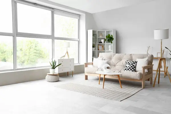 Interior of light living room with cozy sofa and white furniture