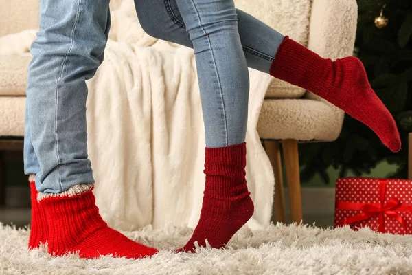 Young couple wearing warm socks in living room decorated for Christmas