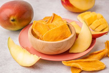 Tahta kase, beyaz masada kurutulmuş mango dilimleri.