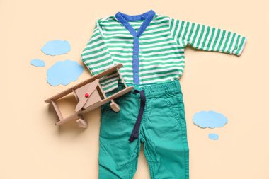 Bebek kıyafetleri, oyuncak uçak ve renkli kağıttan bulutlarla kompozisyon