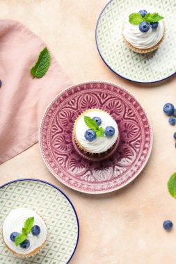 Yaban mersinli lezzetli kekler ve pembe arkaplanda nane şekeri.