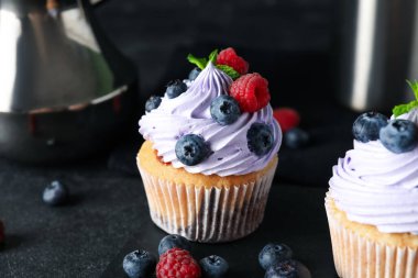 Böğürtlenli, ahududulu ve siyah arkaplanlı lezzetli kekler.