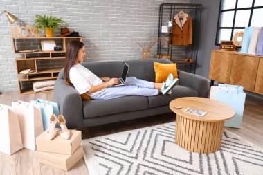 Bilgisayarlı genç Asyalı kadın evde online alışveriş yapıyor.