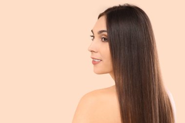 Bej arka planda güzel saçları olan esmer bir kadın.