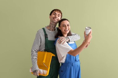 Yeşil arka planda boya kutuları ve tekerlekleri olan genç bir çift.