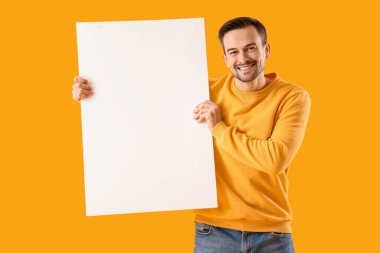 Sarı arka planda boş posteri olan genç adam.