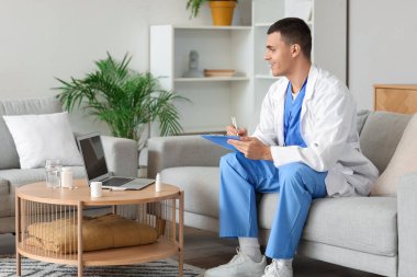 Genç doktor evde dizüstü bilgisayarında hastayla görüntülü sohbet ediyor.