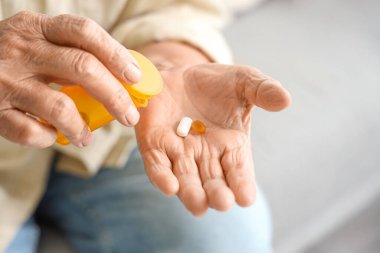 Yaşlı kadın evde hap alıyor, yakın plan.