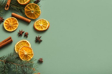 Köknar dallı kurutulmuş portakal dilimleri, tarçın ve yeşil arka planda yıldız anason.