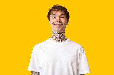 Sarı arka planda mutlu, yakışıklı, dövmeli adam.