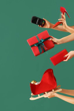 Yeşil arka planda ödeme terminali, ayakkabı ve Noel dekoru olan kadın elleri. Yeni yıl alışveriş konsepti