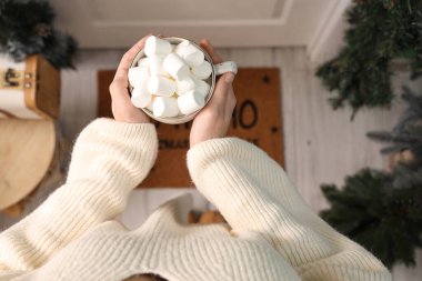 Noel arifesinde elinde marshmallowlu bir fincan kakao tutan bir kadın.
