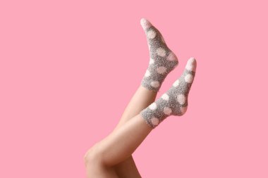 Pembe arka planda sıcak gri noktalı çoraplı genç kadın bacakları.