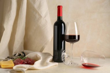 Bej rengi grunge arka planda abur cuburlu kırmızı şarap ve şişe.