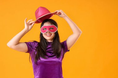 Sarı arka planda karnaval maskeli güzel bir kadın.