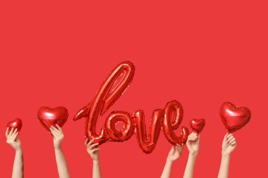 Kelime şeklinde balonları ve kırmızı arka planda kalpleri olan kadın elleri. Sevgililer Günü kutlaması