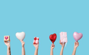 Hediye kutuları ve mavi arka planda kupa şeklinde balonları olan kadın elleri. Sevgililer Günü kutlaması